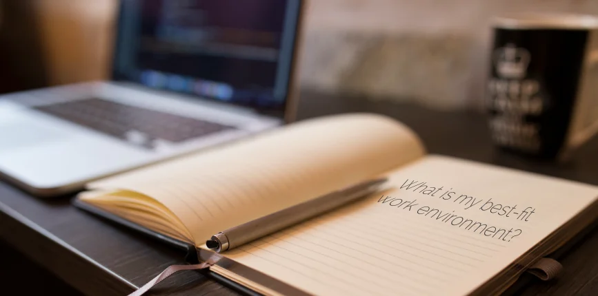 undergoing career assessment open laptop on desk next to open notebook that says, " what is my best fit work environment?"
